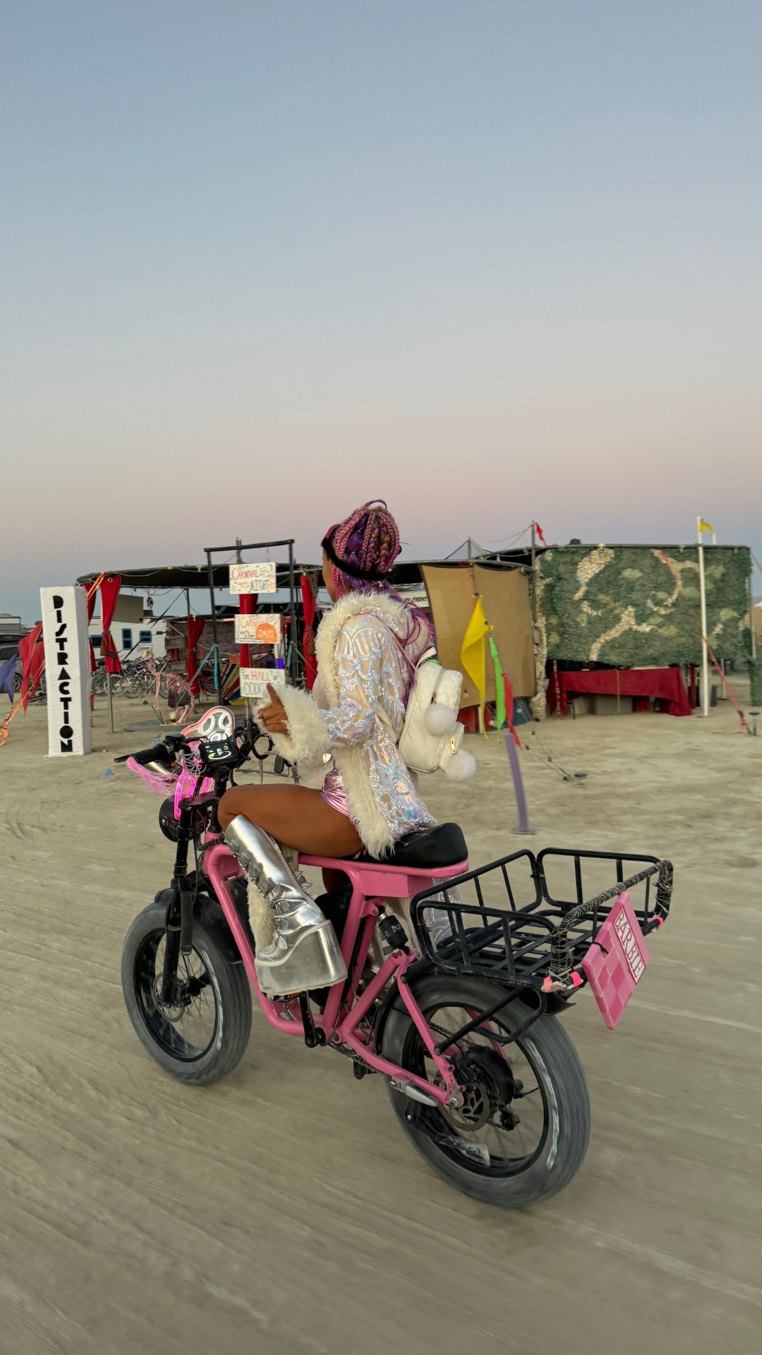 Rider in sequined jacket and silver boots on a pink DUST eBike at dusk in the desert